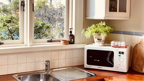 Cucina con lavello in acciaio inossidabile, forno a microonde e finestra vista alberi e casa.
