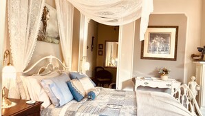 Una camera da letto con un letto a baldacchino, un comodino con una lampada, una cassettiera e uno specchio.