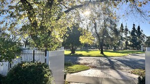 Une allée fermée par un portail mène à un quartier résidentiel agrémenté d’une pelouse et d’arbres.