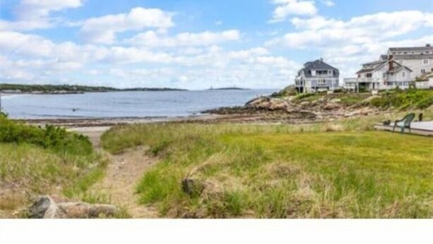 A coastal property with a large house and a smaller building, a grassy area, and a body of water.
