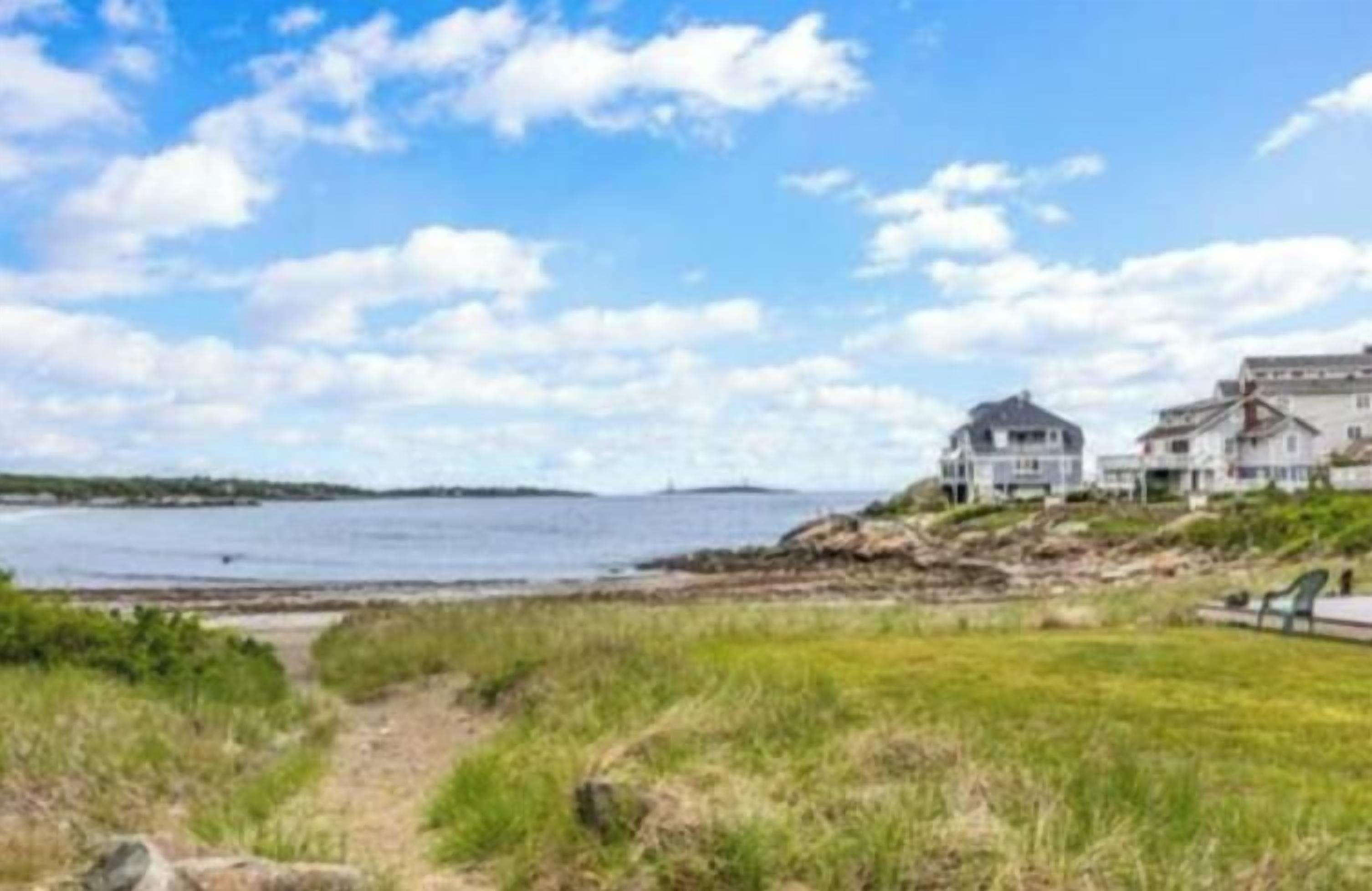 A coastal property with a large house and a smaller building, a grassy area, and a body of water.