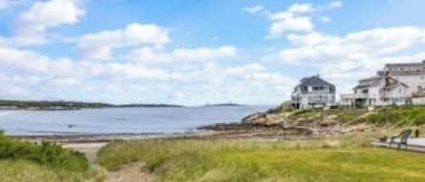 A coastal property with a large house and a smaller building, a grassy area, and a body of water.