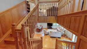 A spacious living area with a wooden staircase, a dining table, and a sofa.