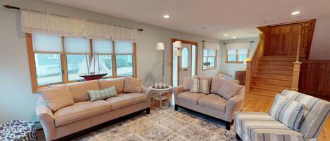 A living room with a beige sofa, a striped armchair, and a patterned rug.