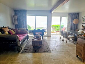 A living room with a sofa, coffee table, and a dining area with chairs and a table.