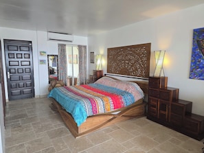 Ein Schlafzimmer mit einem Holzbett, einem großen, dekorativen Kopfteil, einem Nachttisch, einer Lampe und einem Gemälde an der Wand.