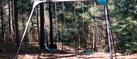 A swing set in a wooded area.