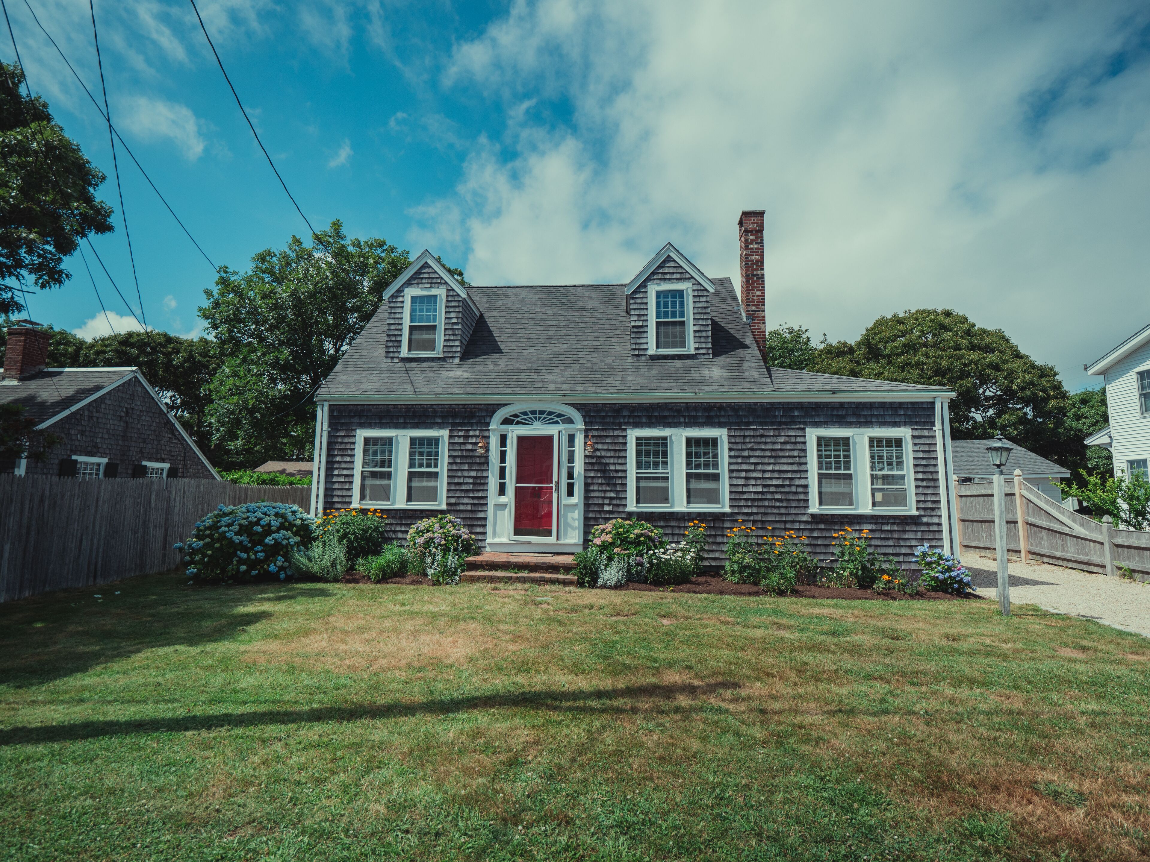 A two-story house with a red door, white trim, and a small front porch.
