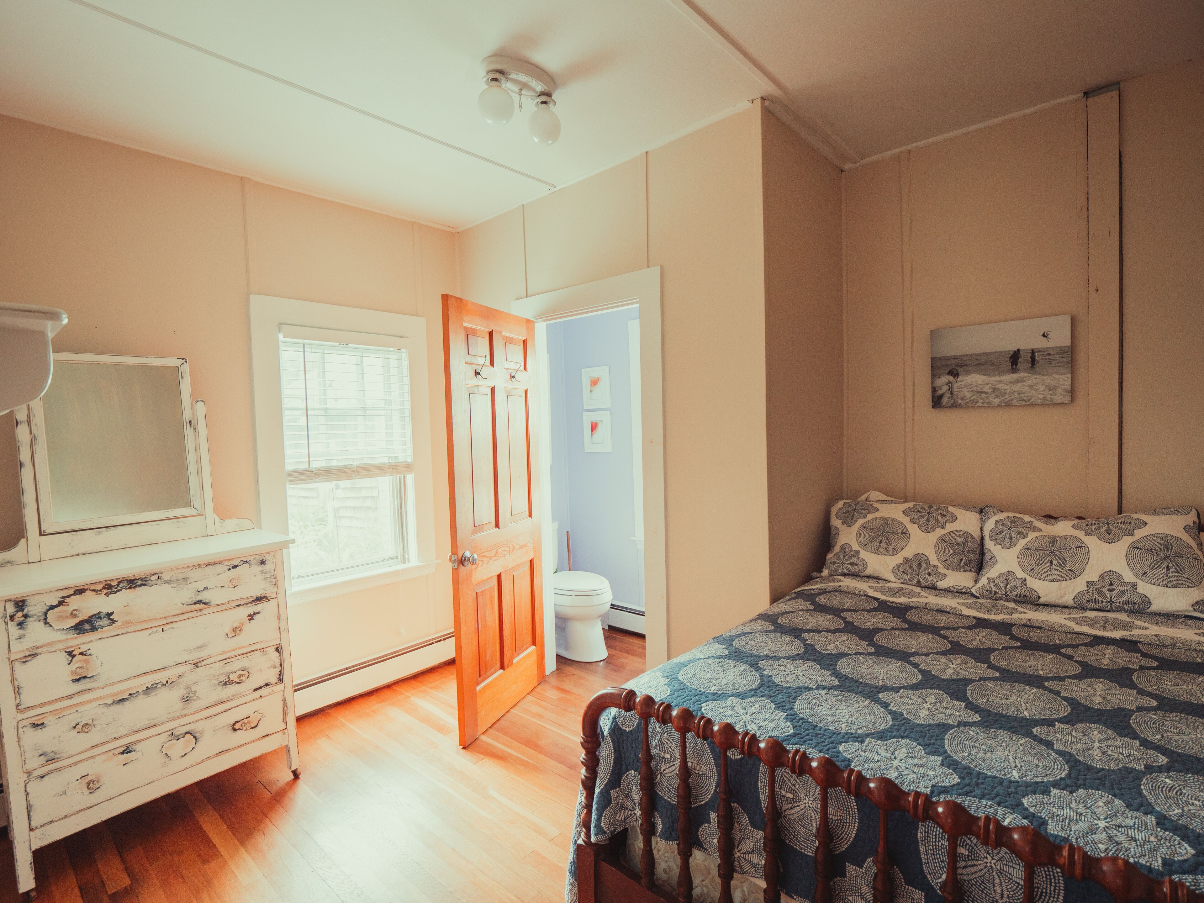 Un dormitorio con cama, cómoda y una puerta que da a otra habitación.