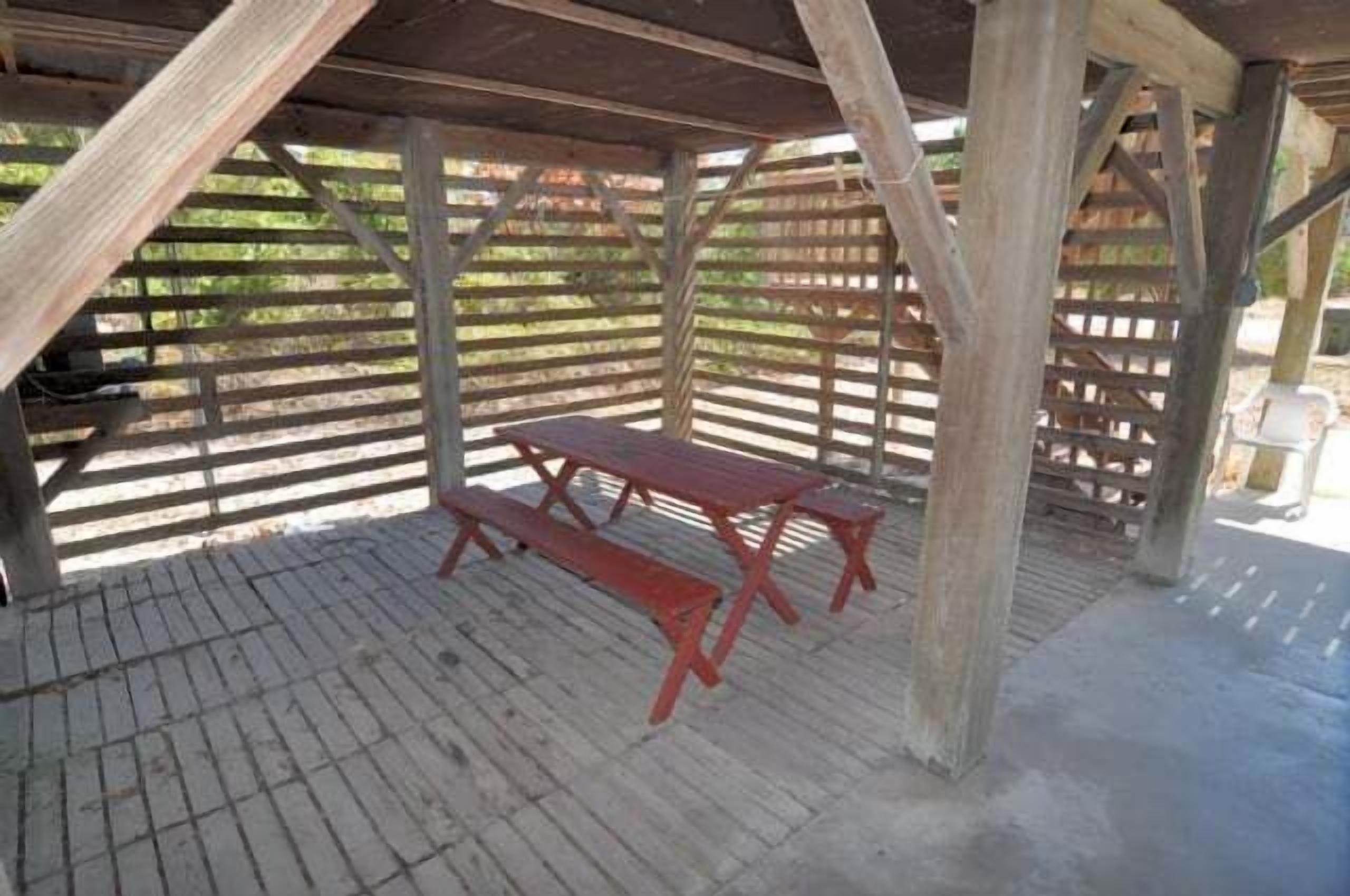 A covered outdoor area with a picnic table and benches.