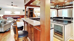 A spacious living area with a pool table, comfortable seating, and a kitchen with a large island and modern appliances.