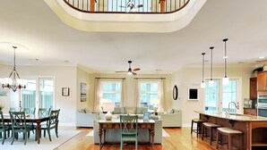 A spacious living area with a dining table, sofas, and a kitchen with a bar.