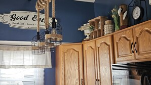 A kitchen with wooden cabinets, a hanging light fixture, and a wall sign. - Lake Erie Beach House In Quiet Communitty. (Huron)