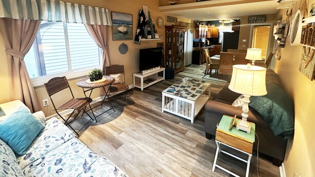 A cozy living room with a television, a dining area, and a kitchen in the background. - Lake Erie Beach House In Quiet Communitty. (Huron)
