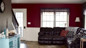 Un salon avec un canapé en cuir marron foncé, un meuble bleu clair et un mur rouge.