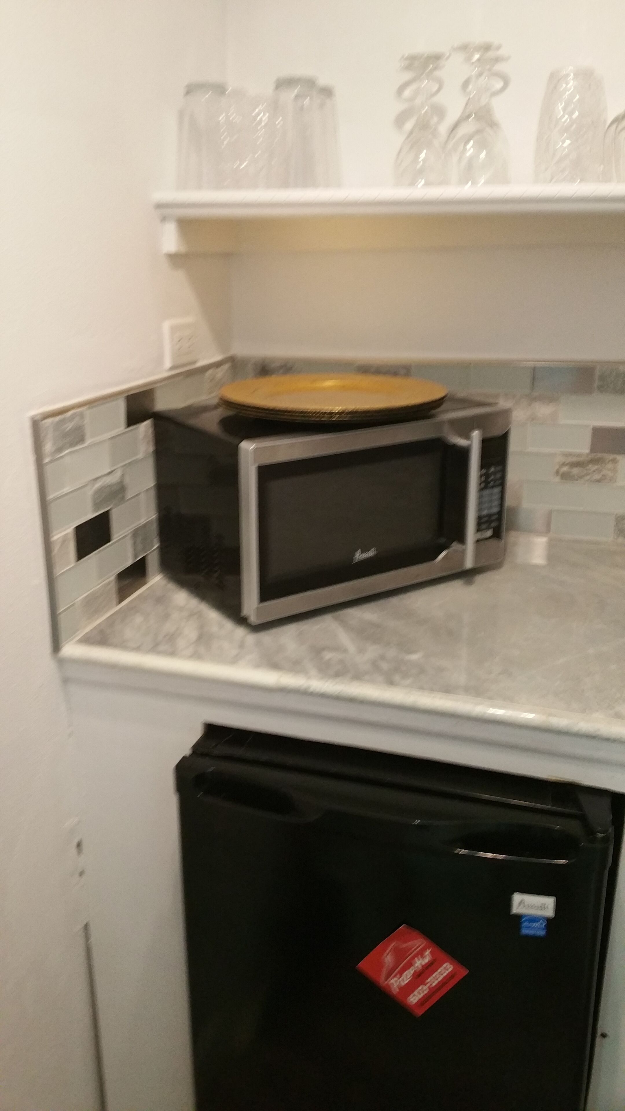 A kitchen with a refrigerator, a microwave, and a sink.