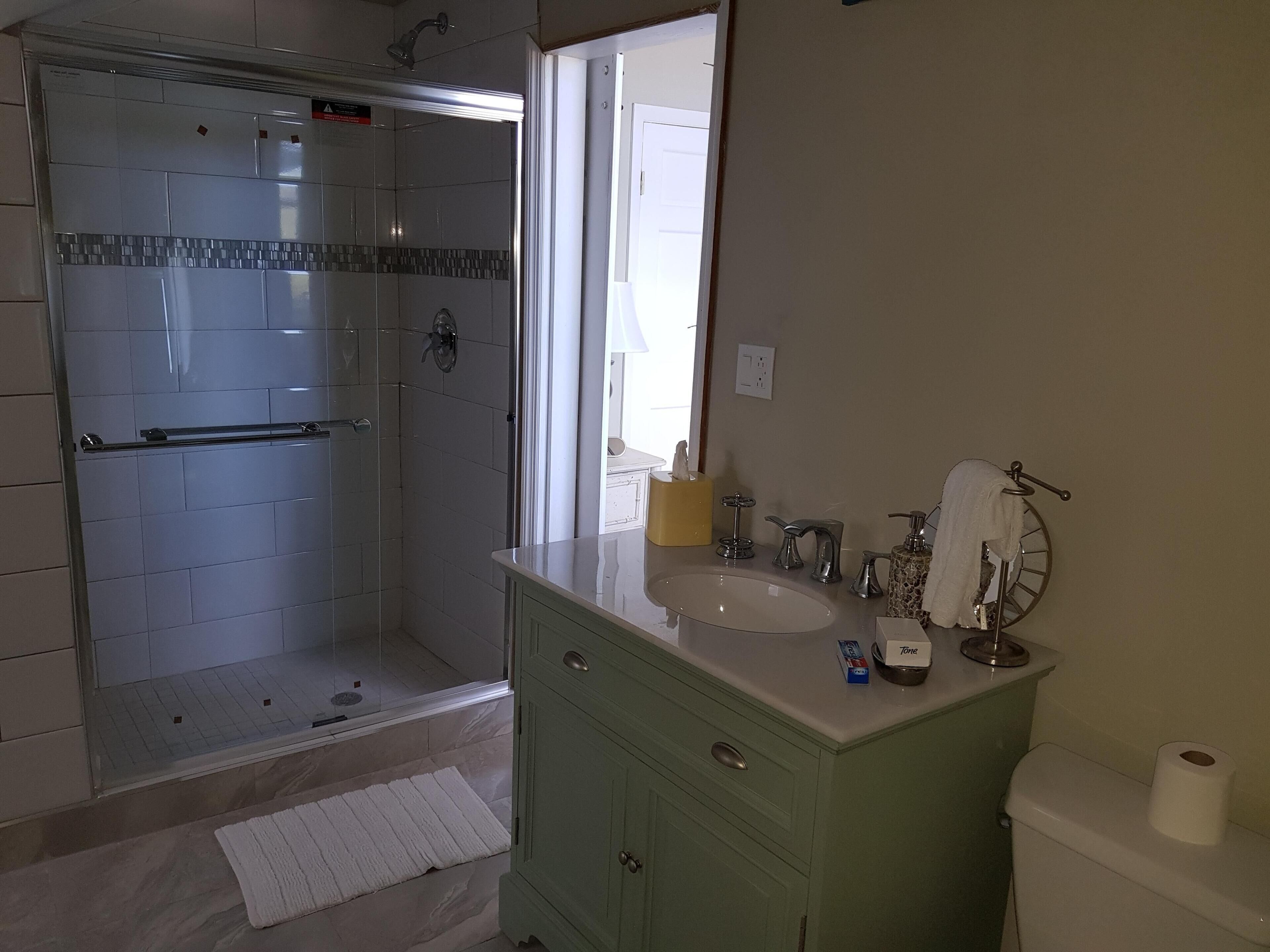 A bathroom with a shower, vanity, and toilet.