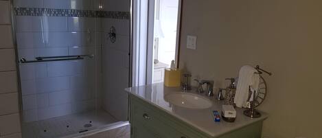 A bathroom with a shower, vanity, and toilet.