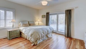 Un dormitorio con cama, mesita de noche y ventana con persianas.
