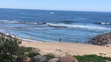 Une plage avec des affleurements rocheux et des vagues.