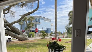 A view from a window with a patterned rug, a potted plant with red flowers, and a stop sign in the background. - SEAS THE DAY: Charming Folly Beach Apartment awaits your arrival! (Folly Beach)