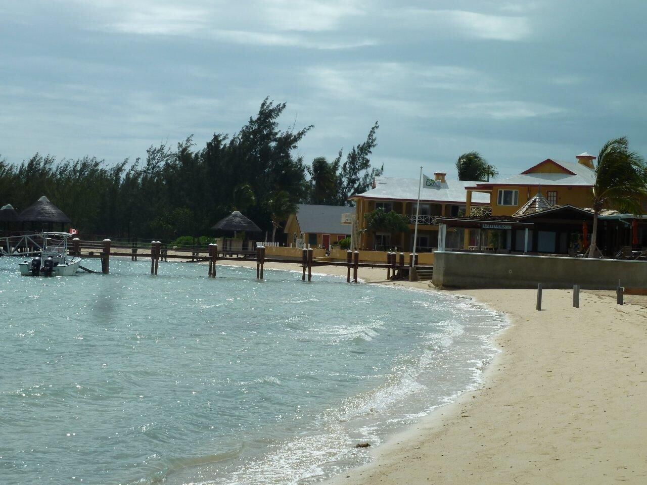 A beach with clear water, a boat dock, and buildings with a beach view.