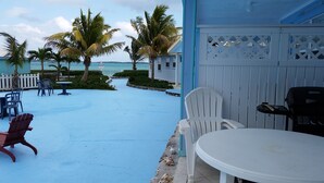 Un área de estar al aire libre con mesas y sillas, una piscina y palmeras.