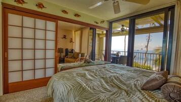 A hotel room with a bed, a chair, a table, and a view of the ocean.