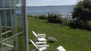 A grassy outdoor area with Adirondack chairs and a glass building. - Ocean Front cottage in Belfast (Belfast)