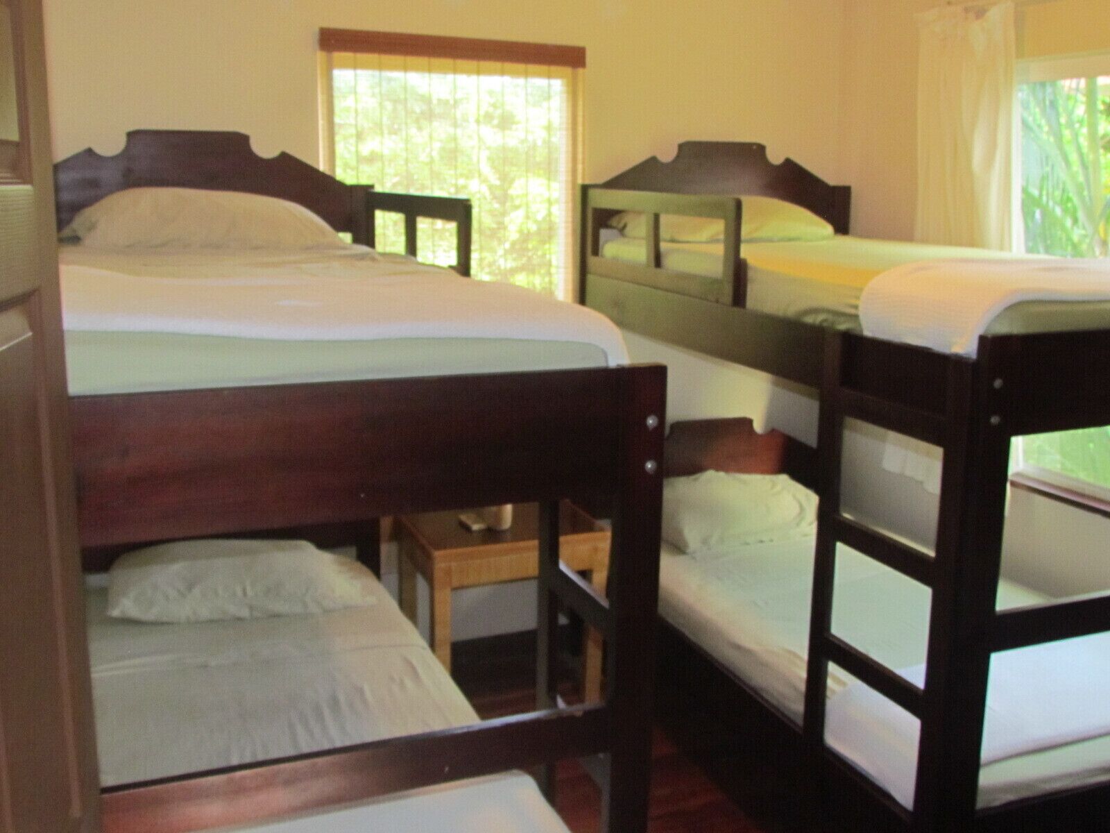 A room with bunk beds, a small wooden table, and a window with blinds.