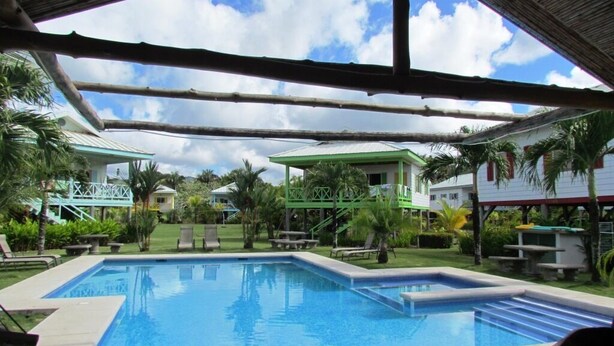 A swimming pool with a view of a resort area, including buildings and palm trees. - Private Oceanview Bungalow #9 (Playa Hermosa)
