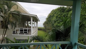 A two-story building with a balcony overlooking a lush garden and a view of the ocean. - Private Oceanview Bungalow #9 (Playa Hermosa)