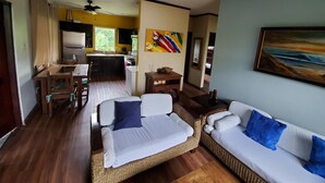 A modern living room with a sofa, a dining area, and a kitchen. - Private Oceanview Bungalow #9 (Playa Hermosa)