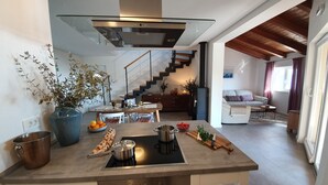 Een moderne keuken met een kookeiland, een eethoek en een trap naar een woonkamer.