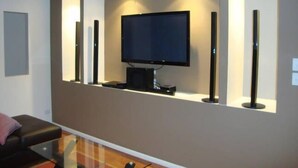 A modern living room with a flat-screen TV mounted on a wall, surrounded by built-in shelving units. - Kooroora House -Spa Bath-Pool- Billard Table (Robina)