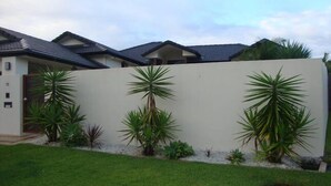 A modern house with a flat roof, a white exterior wall, and a well-maintained lawn. - Kooroora House -Spa Bath-Pool- Billard Table (Robina)