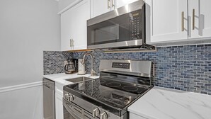Uma cozinha moderna com eletrodomésticos de aço inoxidável, armários brancos e um backsplash com azulejos azuis.