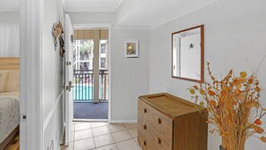 A room with a wooden dresser, a framed picture, and a view to a balcony with a pool. - Summer is booking fast! Please book soon. New paint and upgrades!!! (Hilton Head Island)