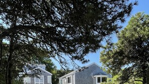 A two-story house with a gravel driveway and a garage. - Katama House w/Guest House w/AC South Beach heated pool. 
Summer weeks avail. 
 (Edgartown)