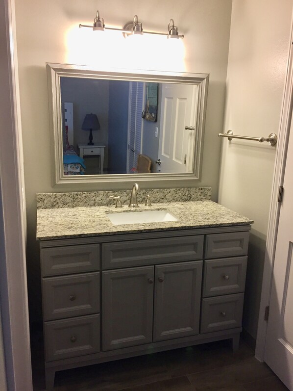 A bathroom with a granite countertop, a sink, and a large mirror. - Beach View Condo. Professionally Cleaned, Flexible Booking! (Gulf Shores)