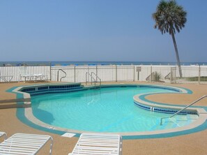 A swimming pool with a palm tree and a view of the ocean. - Beach View Condo. Professionally Cleaned, Flexible Booking! (Gulf Shores)
