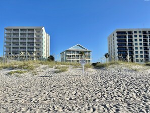 Um hotel à beira-mar com vários andares, uma placa indicando 'Southern Sands 417 West Beach Blvd.' e uma praia de areia em primeiro plano.