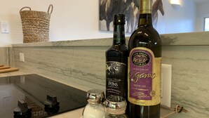 En köksbänk med flaskor av Pons Pasion Familiar och Napa Valley Naturals extra jungfruolja, saltströare och en flätad korg.
