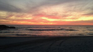 Een strand met golven en een zonsondergang.