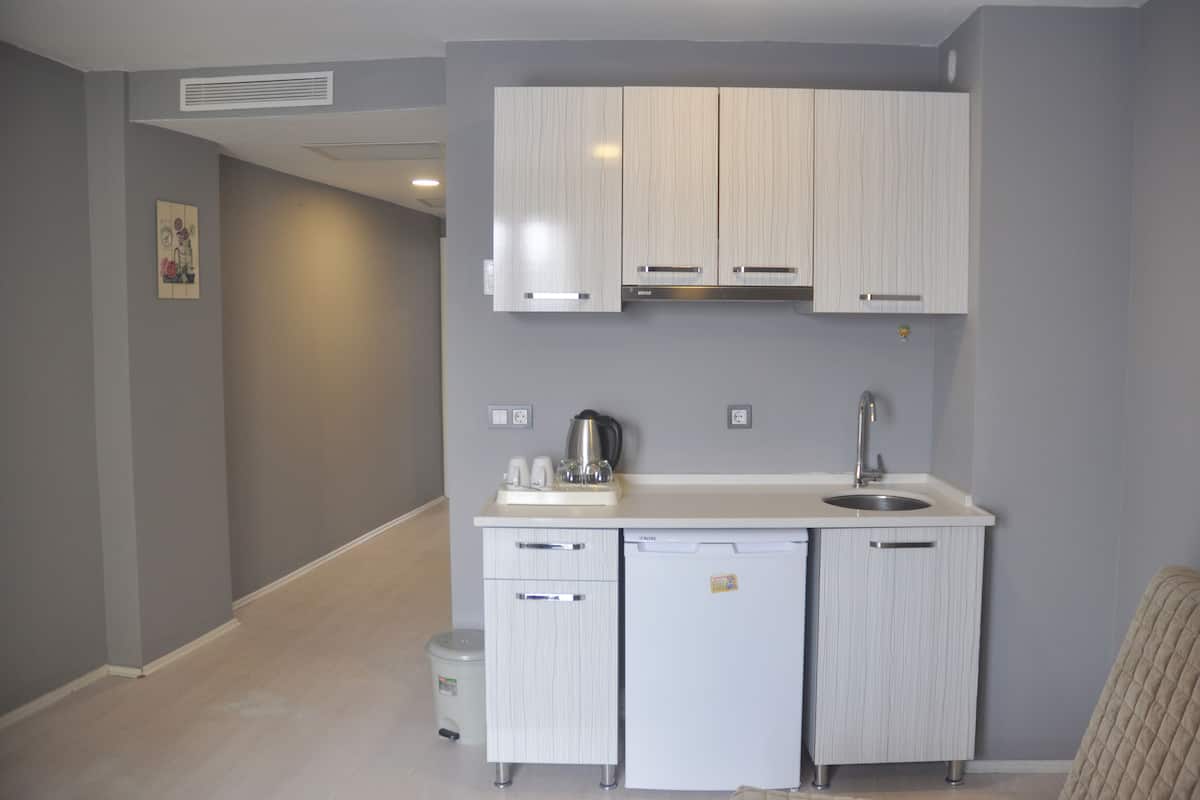 A compact kitchen with white cabinetry, a sink, and a small refrigerator.