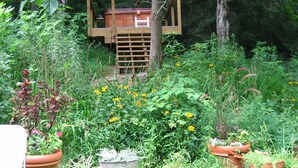A garden with a wooden structure, possibly a playhouse or storage shed, surrounded by various potted plants and flowers.