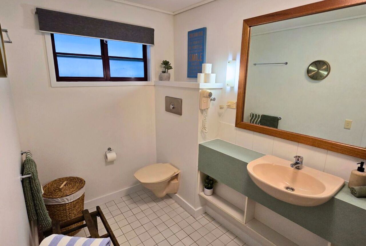 A small bathroom with a toilet, sink, and window.
