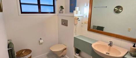A small bathroom with a toilet, sink, and window.