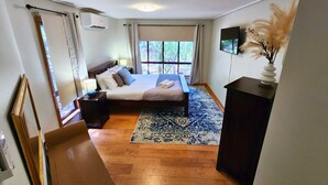 A bedroom with a bed, bedside tables, a TV, and a window with curtains. - Sapphire Villa 535, Kingfisher Bay Resort, K'gari (Fraser Island)