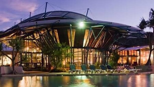 A modern hotel with a unique dome-like structure, a swimming pool, and lounge chairs. - Sapphire Villa 535, Kingfisher Bay Resort, K'gari (Fraser Island)